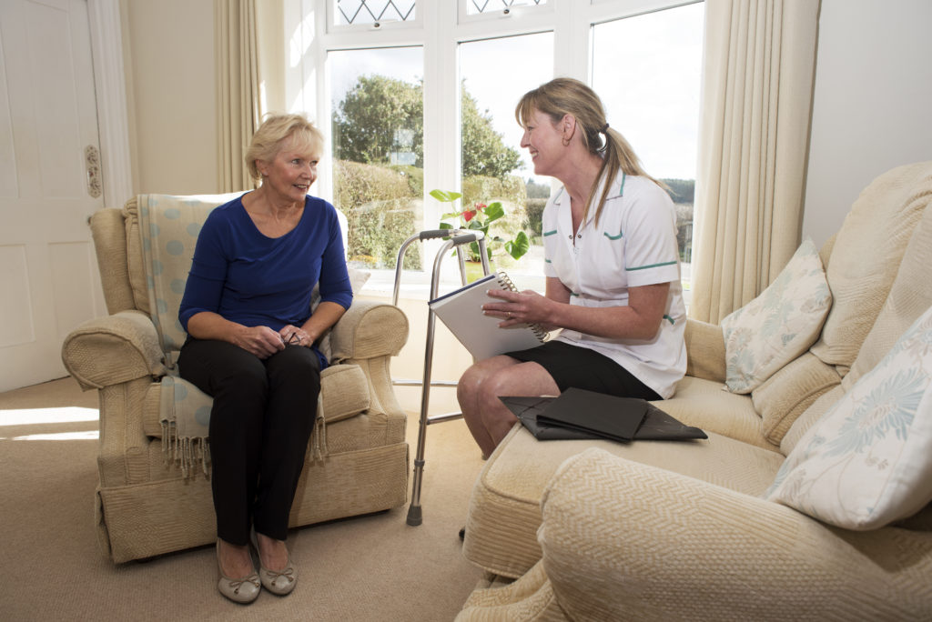 Nurse on a home visit talking with an elderly female patient